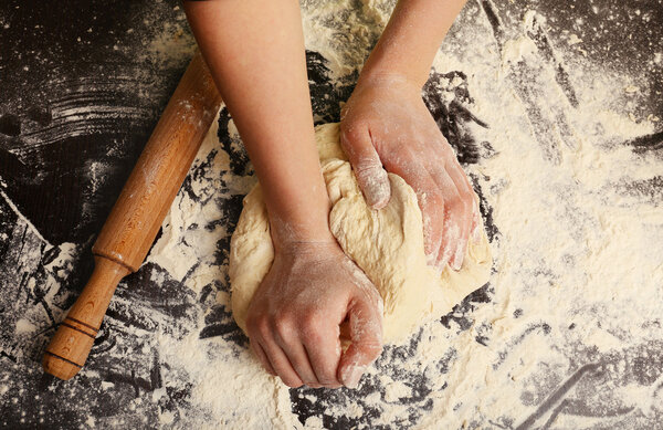 Making dough by female hands on wooden table background