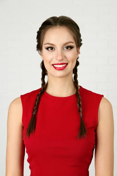 Hübsche Frau mit Frisur im roten Kleid auf hellem Hintergrund — Stockfoto