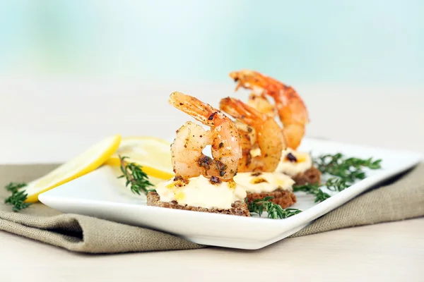 Appetizer canape with shrimp and lemon on table on light background — Stock Photo, Image