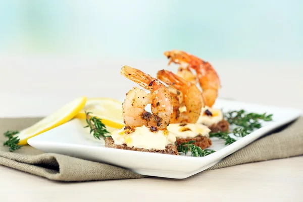 Canapé de aperitivo con camarones y limón sobre la mesa sobre fondo claro — Foto de Stock