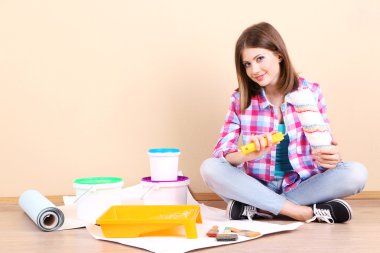 Güzel kız boyama duvar için ekipman ile katta oturan