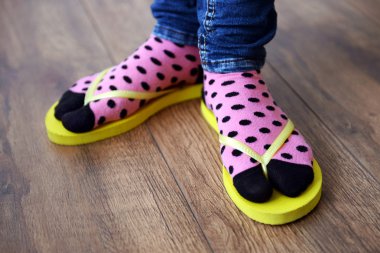 Kat zemin üzerine pembe parmak arası terlik ile çoraplı kadın ayakları