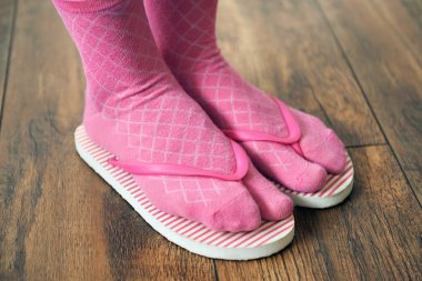Kat zemin üzerine pembe parmak arası terlik ile çoraplı kadın ayakları