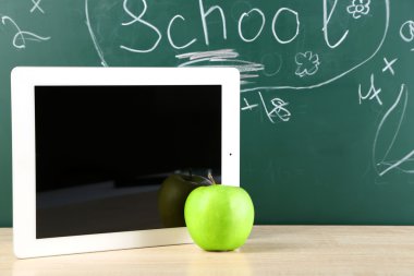 Dijital tablet ve elma yazı tahtası önünde masa üzerinde