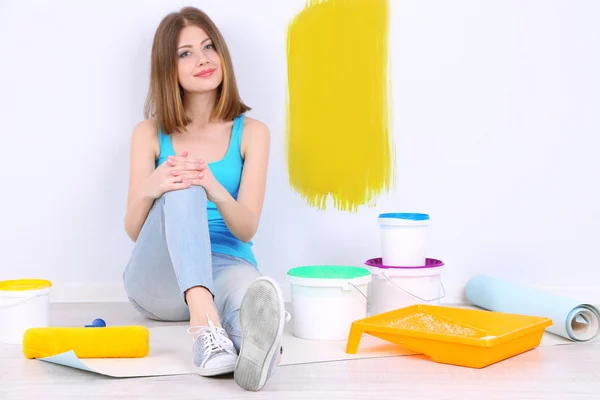 Menina bonita sentada no chão com equipamento para pintura de parede — Fotografia de Stock