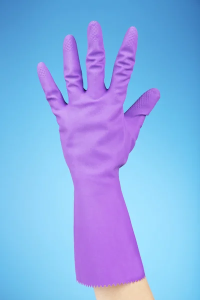 Rubberen handschoen op hand, op blauwe achtergrond — Stockfoto