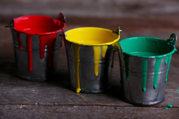 Baldes de metal com tinta colorida sobre fundo de madeira — Fotografia de Stock