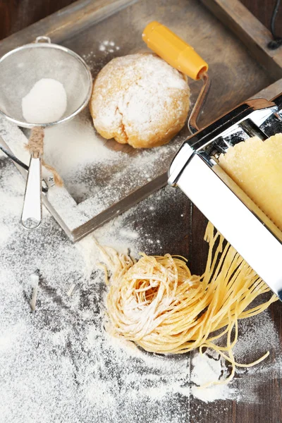 Hacer vermicelli con máquina de pasta y harina espolvoreada sobre fondo de madera —  Fotos de Stock