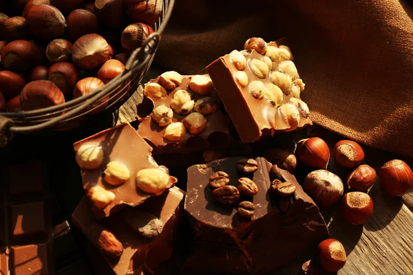 Bodegón con conjunto de chocolate con nueces en la mesa de madera, primer plano —  Fotos de Stock