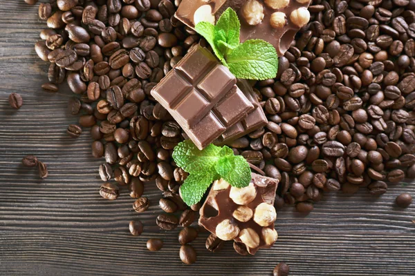 Chocolade met munt en koffie bonen op houten tafel, close-up — Stockfoto