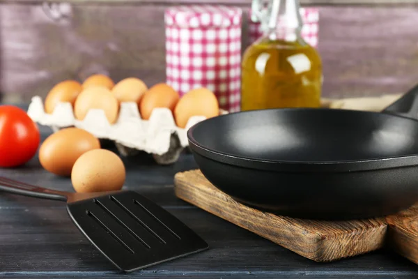 Still life with eggs and pan on wooden background — Stock Photo, Image