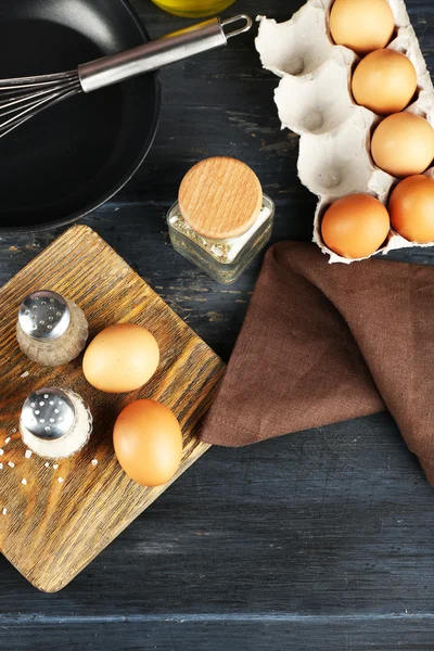 लकड़ी की मेज पर अंडे और पैन के साथ अभी भी जीवन, शीर्ष दृश्य — स्टॉक फ़ोटो, इमेज