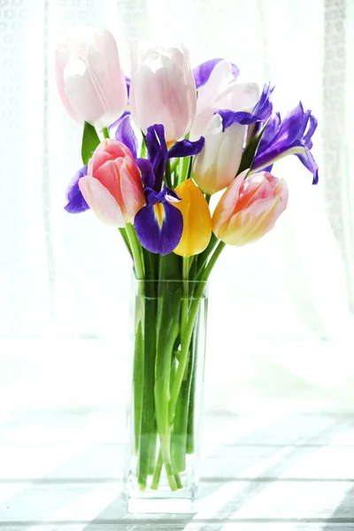 Mooi boeket van Lentebloemen in glazen vaas op gordijn achtergrond — Stockfoto