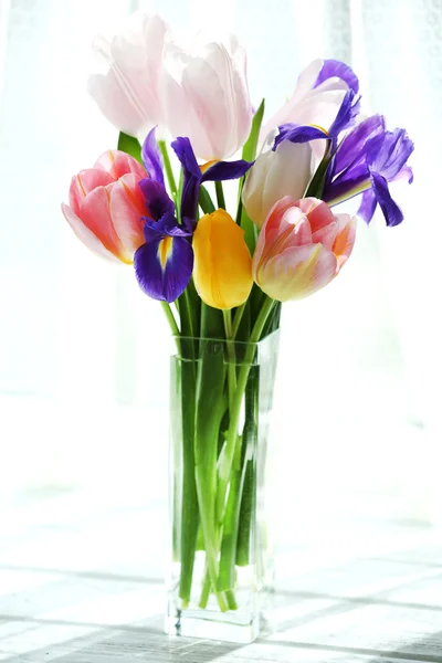 Mooi boeket van Lentebloemen in glazen vaas op gordijn achtergrond — Stockfoto