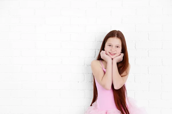 Mooie kleine ballerina op witte bakstenen muur achtergrond — Stockfoto