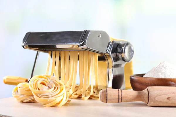 Att göra nudlar med pasta maskin på ljus bakgrund — Stockfoto