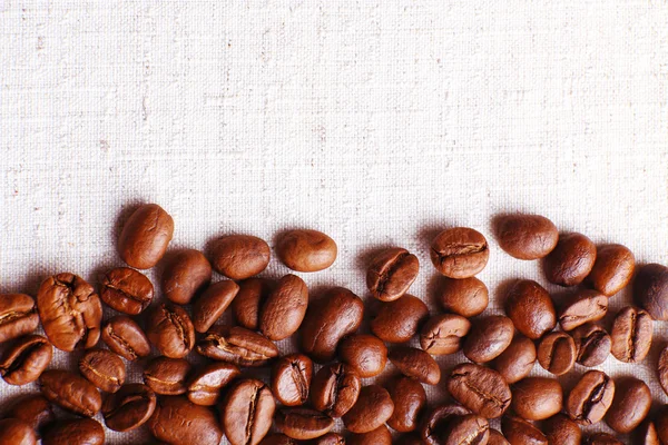 Frame of coffee beans on color sackcloth background — Stock Photo, Image