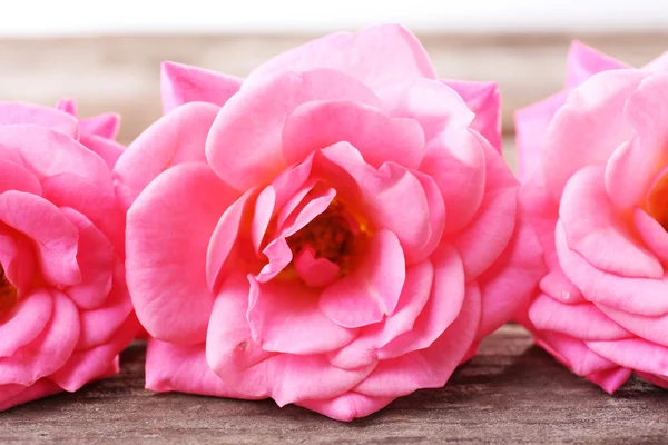 Mooie roze rozen op houten tafel, close-up — Stockfoto