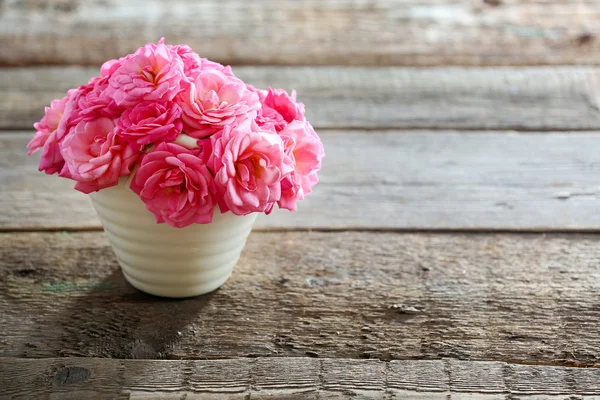 Schöne rosa Rosen im Topf auf Holzgrund — Stockfoto