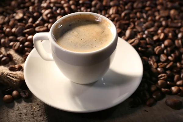 Kopp kaffe och spannmål på träbord med säckväv, närbild — Stockfoto