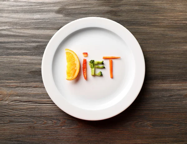 DIETA palabra hecha de verduras en rodajas en plato sobre mesa de madera, vista superior — Foto de Stock