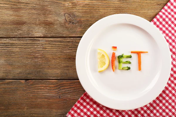 Word DIET made of sliced vegetables in white plate on wooden background — Stock Photo, Image