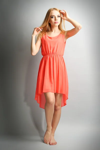 Expressive young model in orange dress on gray background — Stock Photo, Image