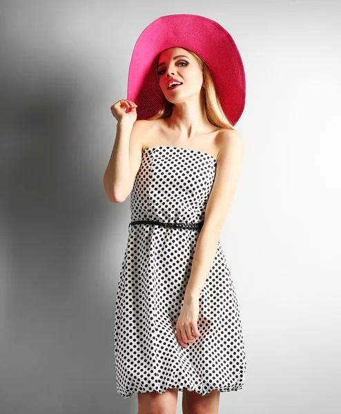 A rózsaszín kalapot, szürke háttér kifejező fiatal modell — Stock Fotó