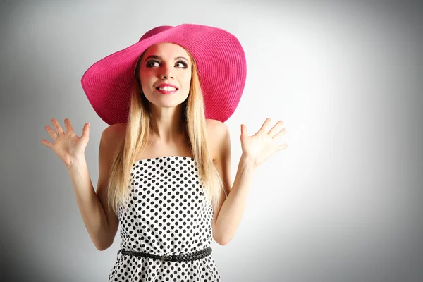 Modelo joven expresivo en sombrero rosa sobre fondo gris —  Fotos de Stock