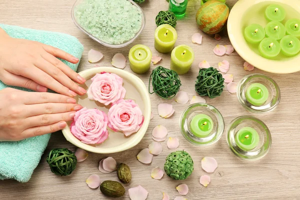 Manos femeninas y tazón de agua de spa con flores, primer plano — Foto de Stock