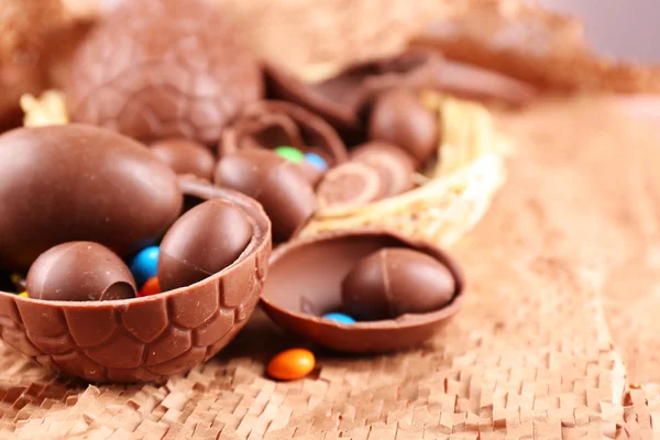 Chocolate Easter eggs on wicker fabric in nest, closeup — Stock Photo, Image