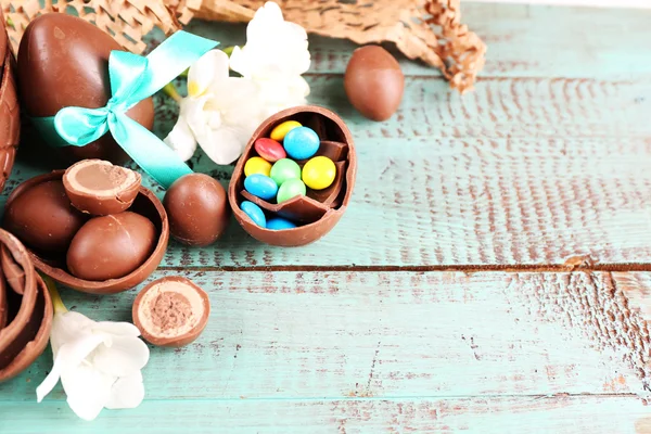 Schokoladen-Ostereier mit Blumen auf Holztisch, Nahaufnahme — Stockfoto