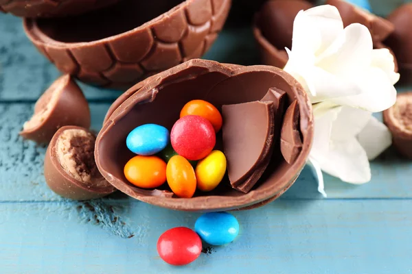 Ovos de Páscoa de chocolate com flores na mesa de madeira, close-up — Fotografia de Stock