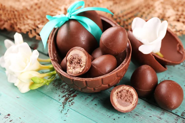 Choklad påskägg med blommor på träbord, närbild — Stockfoto