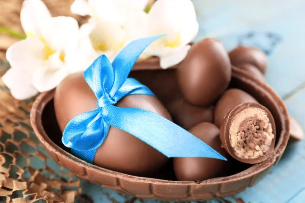 Chocolade paaseieren met bloemen op houten tafel, close-up — Stockfoto