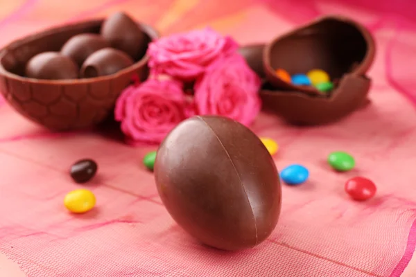 Chocolate Easter eggs with flowers on color tulle, closeup — Stock Photo, Image