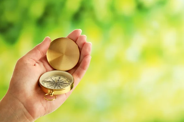 Weibliche Hand mit Kompass auf hellem, verschwommenem Hintergrund — Stockfoto