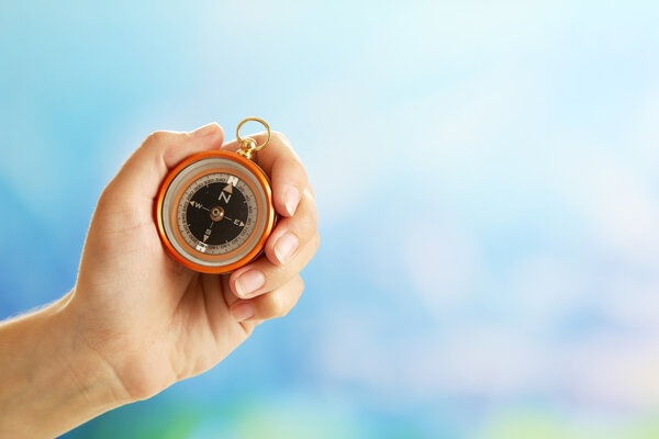 Female hand with compass on bright blurred background