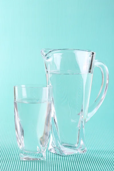 Jarro de vidro e vidro de água no fundo azul — Fotografia de Stock