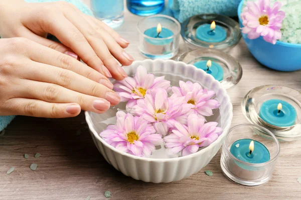 Mãos femininas com tigela de água de spa de aroma em mesa de madeira, close-up — Fotografia de Stock