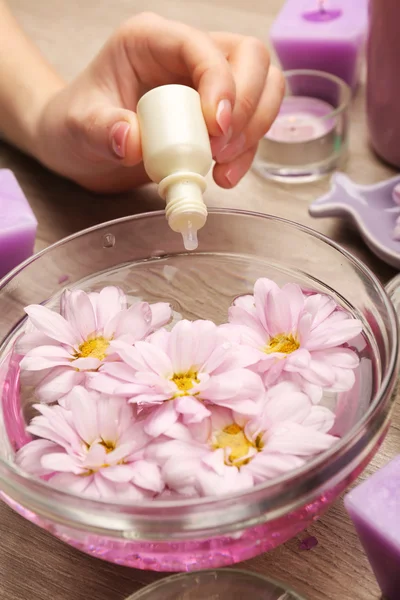 Kvinnlig hand med flaska essens och skål med aroma spa vatten på träbord, närbild — Stockfoto