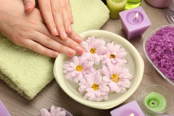 Manos femeninas con tazón de agua spa aroma en mesa de madera, primer plano — Foto de Stock