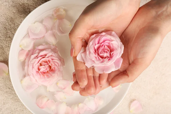 Manos femeninas con tazón de agua de spa aroma en la mesa, primer plano — Foto de Stock