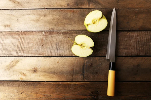Geschnittener Apfel mit Messer auf Holzgrund — Stockfoto