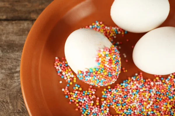 Decorating Easter eggs on color plate on wooden table, closeup — Stock Photo, Image