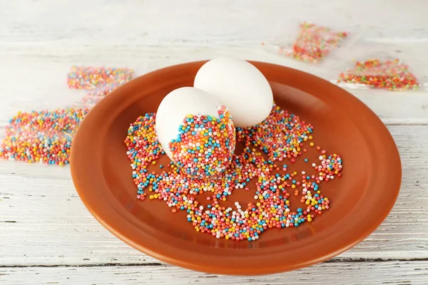 Украшение пасхальных яиц на цветовой пластине на деревянном столе, крупный план — стоковое фото