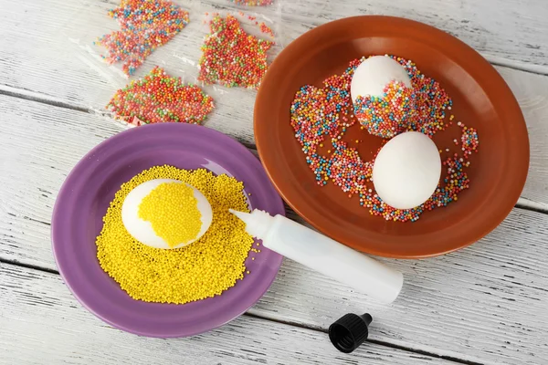 Decorating Easter eggs on color plate on wooden table, closeup — Stock Photo, Image