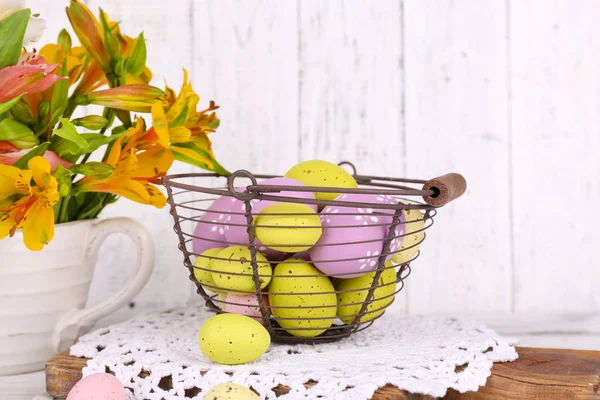 Composizione pasquale con uova di Pasqua in cesto e fiori, su fondo di legno — Foto Stock