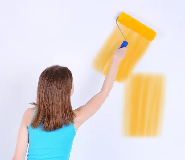 Beautiful girl paints wall in room Stock Photo