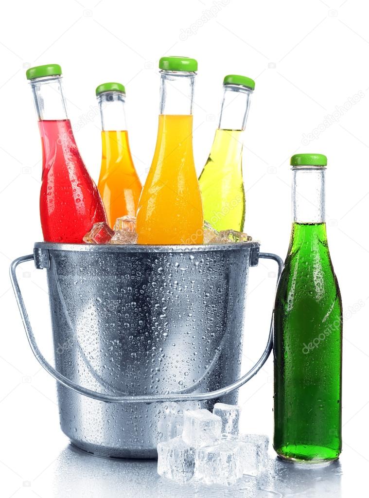 Bottles of tasty drink in metal bucket with ice isolated on white